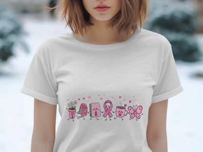 White t-shirt featuring a pink ribbon, notebook, shoe, cup, and butterfly illustration.