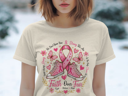 Pink ribbon, sneakers, butterflies, flowers, and text about strength and faith on a t-shirt.