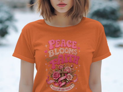 Orange t-shirt with "Peace Blooms Through Faith" graphic featuring a cross and roses.