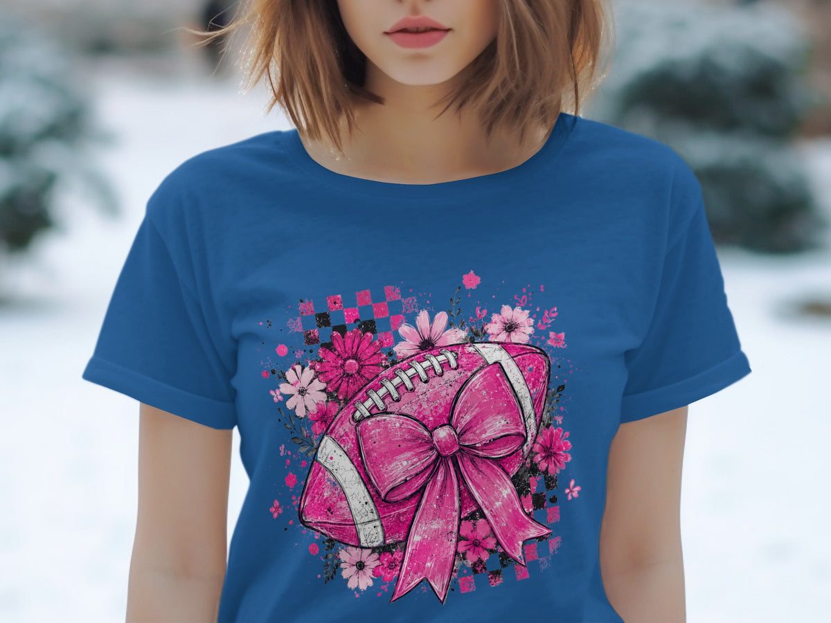 Pink football with bow and flowers graphic on a blue t-shirt.