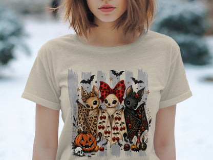 Three cartoon bats with large eyes and Halloween motifs on a light-colored t-shirt.