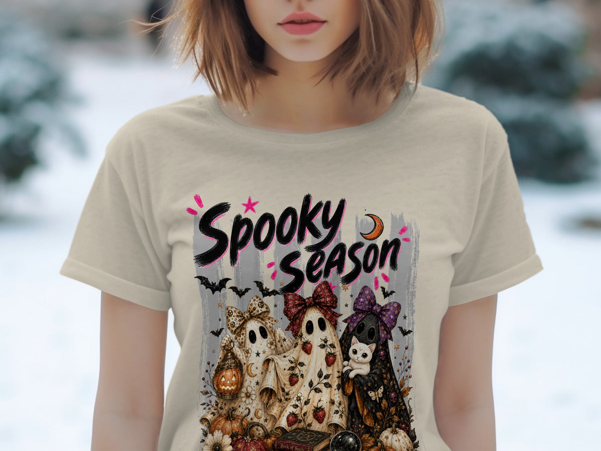 Three cartoon ghosts with bows, a cat, and Halloween decorations on a shirt.