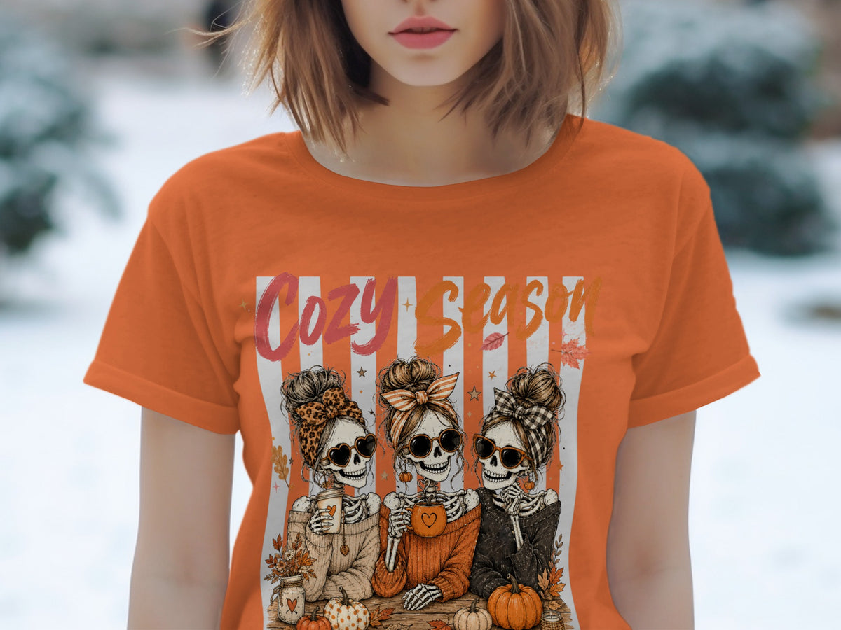 T-shirt with "Cozy Season" text and three skeleton girls with pumpkins.