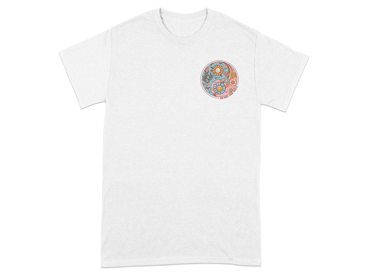 White t-shirt with a circular yin yang design featuring smiling flowers and the text "BALANCE OVER HUSTLE".