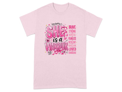 Pink t-shirt with "SHE is a WARRIOR" graphic, featuring positive attributes and a pink ribbon.