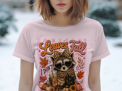 T-shirt graphic with raccoon, cat, and text "Leaves Fall I Don't".