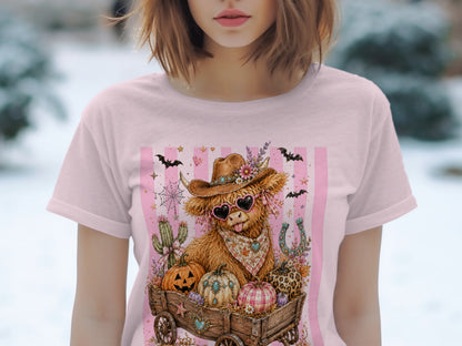 Highland cow with cowboy hat and pink heart sunglasses in a wagon of pumpkins.