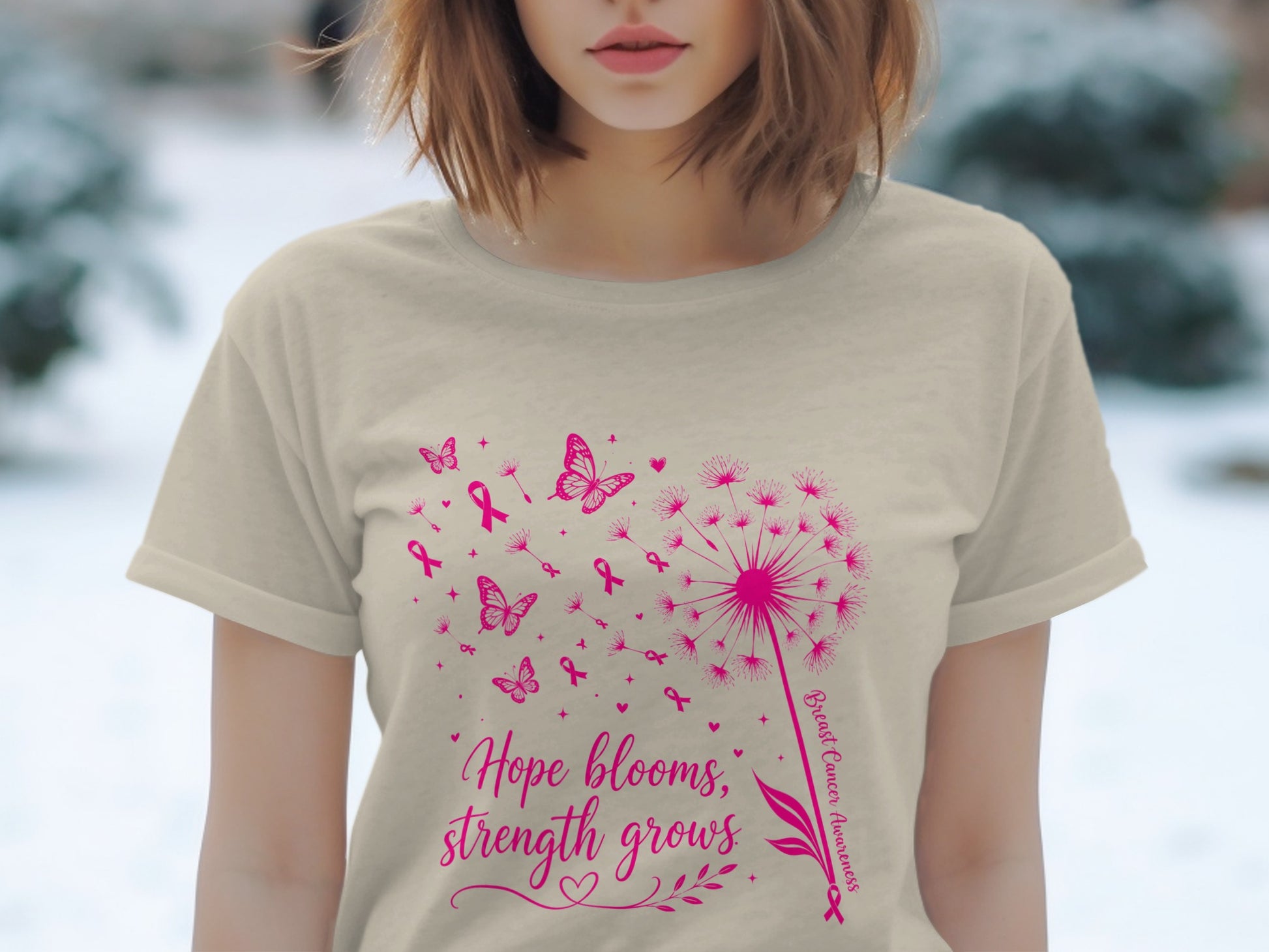 Light tan t-shirt with pink dandelion, butterflies, ribbons, and text "Hope blooms, strength grows."