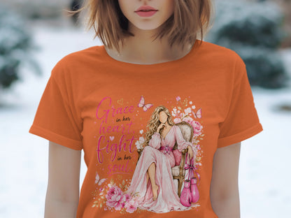 Orange t-shirt graphic with woman, pink boxing gloves, and text "Grace in her heart, fight in her soul."
