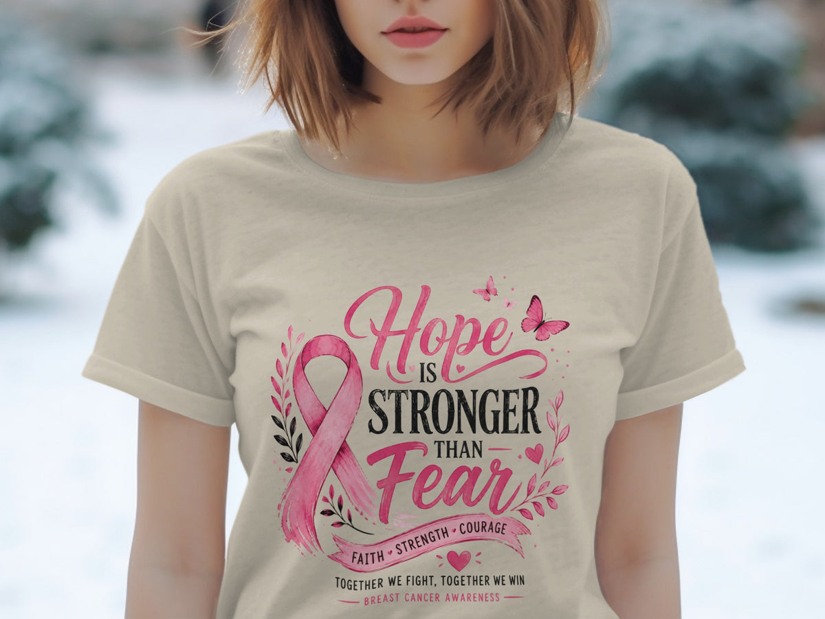 Light tan t-shirt with pink breast cancer ribbon and text: "Hope is Stronger Than Fear."