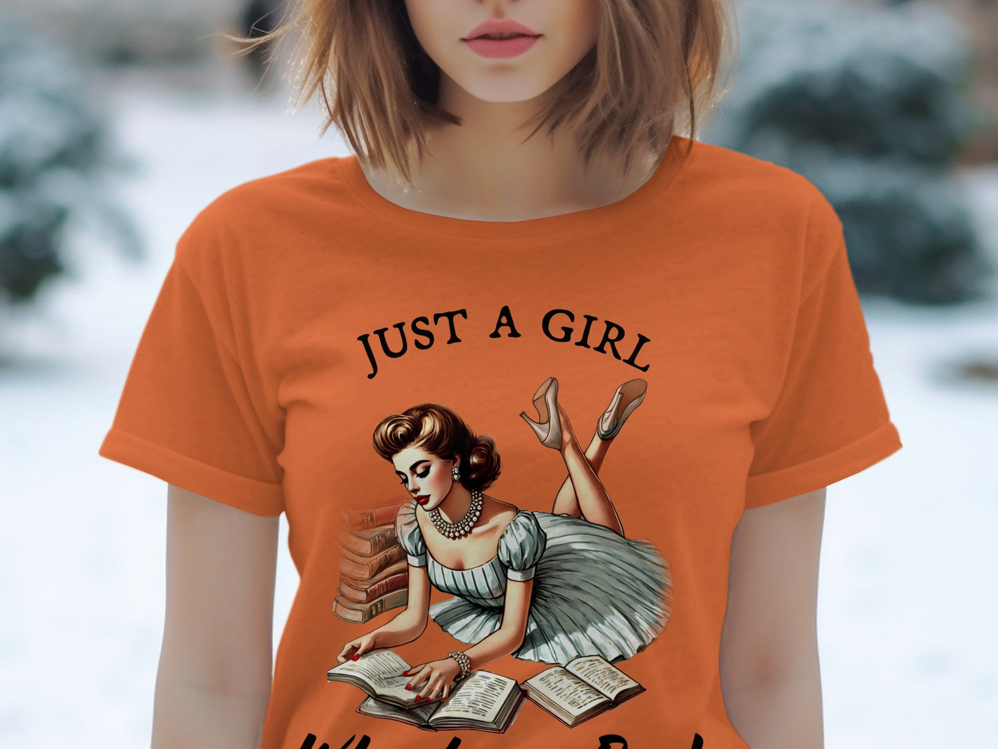 Orange t-shirt with "JUST A GIRL" and illustration of a woman reading books.