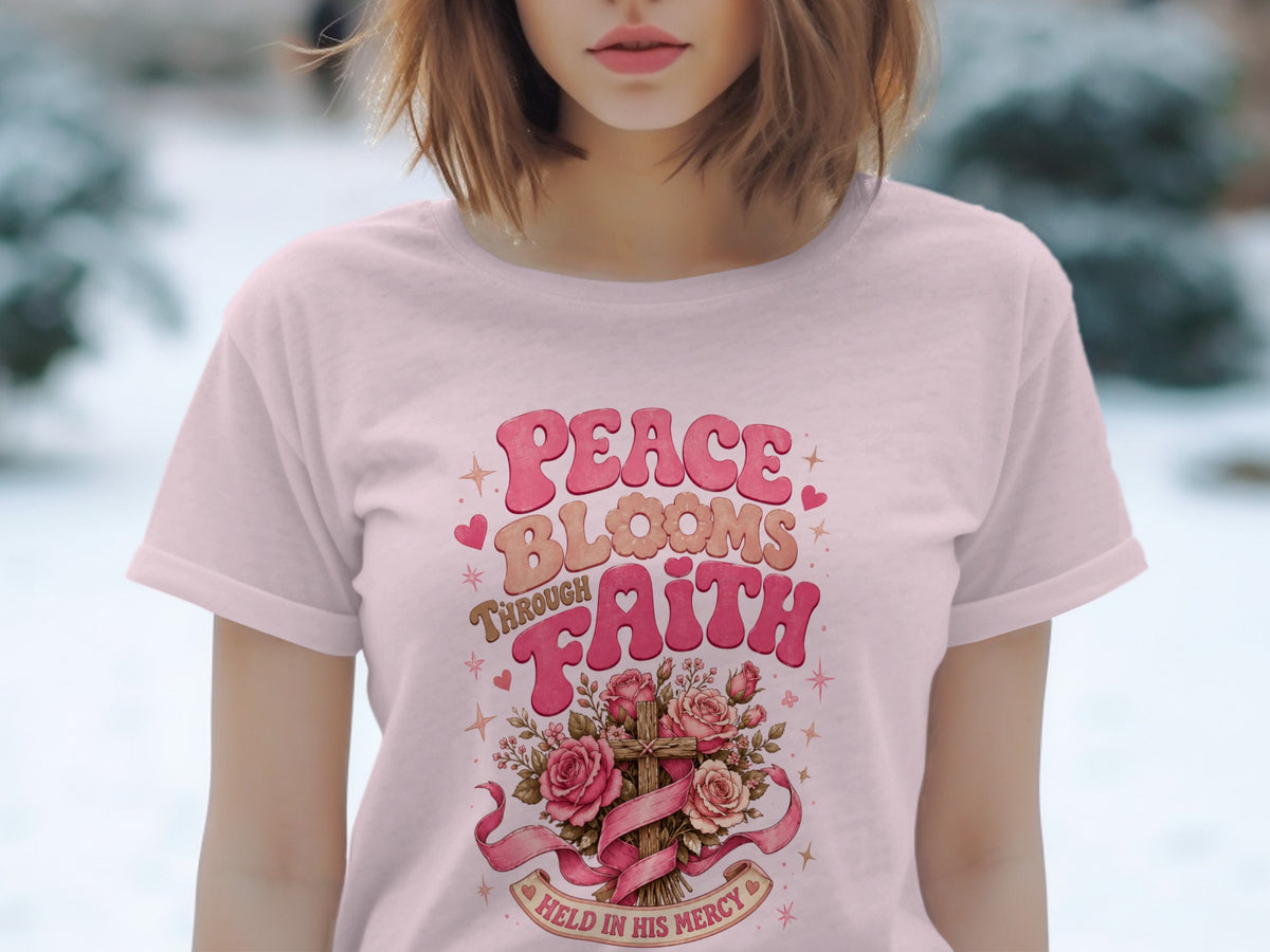 Pink t-shirt with "Peace Blooms Through Faith" text and floral cross design.