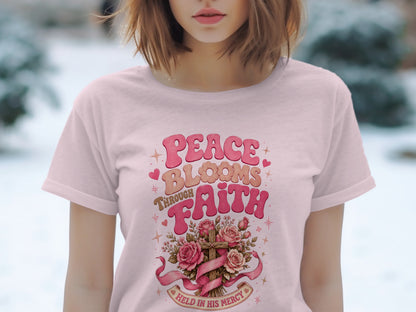 Pink t-shirt with "Peace Blooms Through Faith" text and floral cross design.
