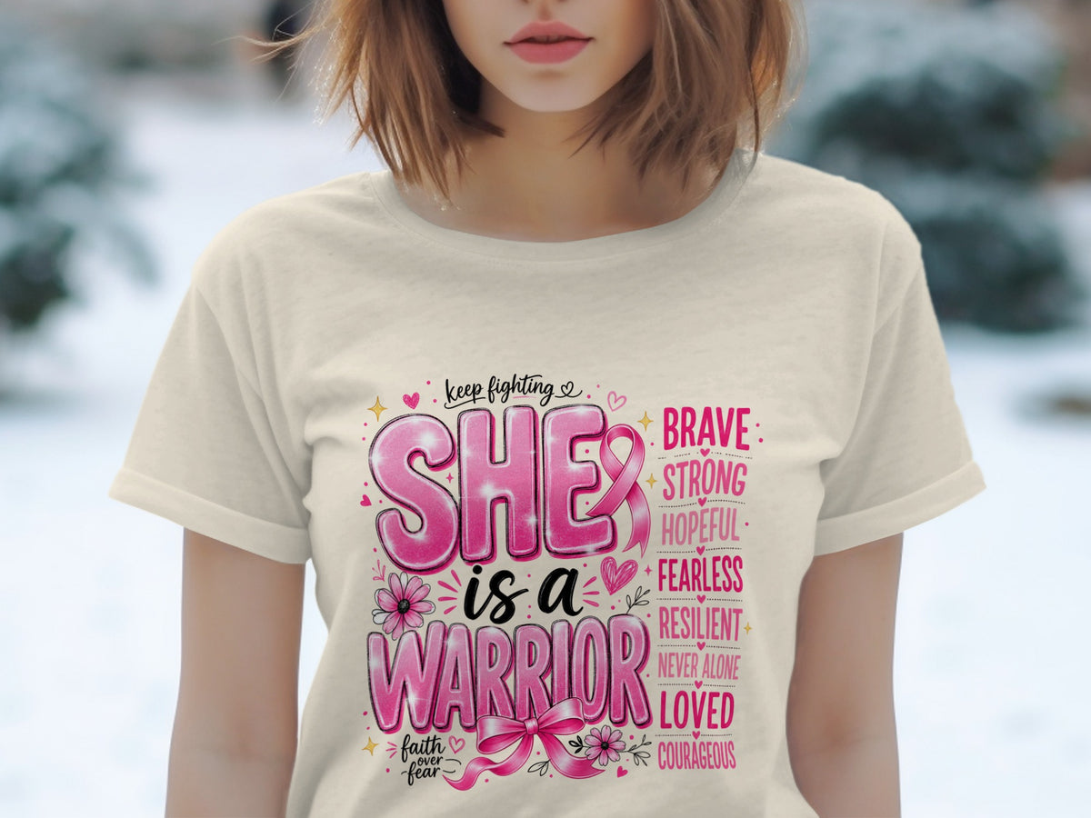 T-shirt graphic with "SHE is a WARRIOR" and supportive words, featuring pink ribbons.