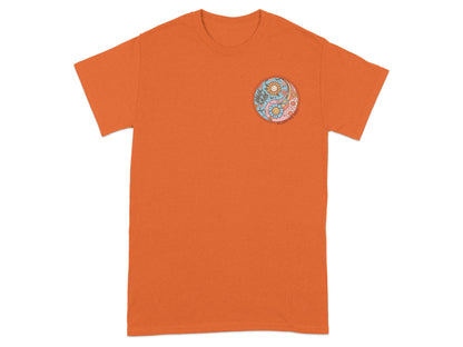 Orange t-shirt with a yin-yang symbol featuring flowers and smiling suns.