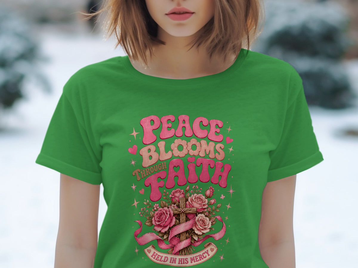 Green t-shirt with "Peace Blooms Through Faith" and a cross with roses.