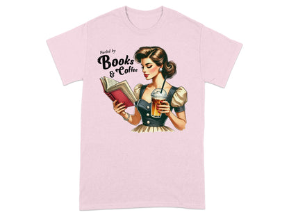 Pink t-shirt with illustration of woman reading book, holding coffee, text "Fueled by Books & Coffee".