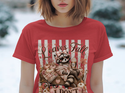 Red t-shirt with a raccoon in sunglasses sitting in a wagon, text "Leaves Fall"