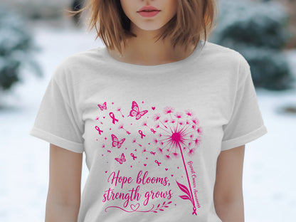 White t-shirt with pink dandelion, butterflies, ribbons, and text "Hope blooms, strength grows".