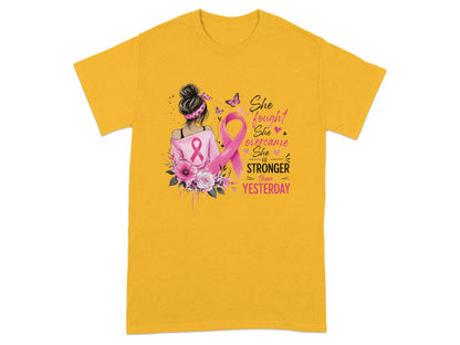 Yellow t-shirt with pink ribbon, flowers, and text "She fought, She overcame, She is STRONGER than YESTERDAY."