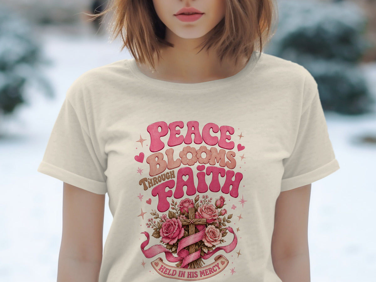 Cream t-shirt with "Peace Blooms Through Faith Held in His Mercy" text and floral cross design.