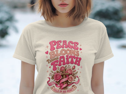 Cream t-shirt with "Peace Blooms Through Faith Held in His Mercy" text and floral cross design.