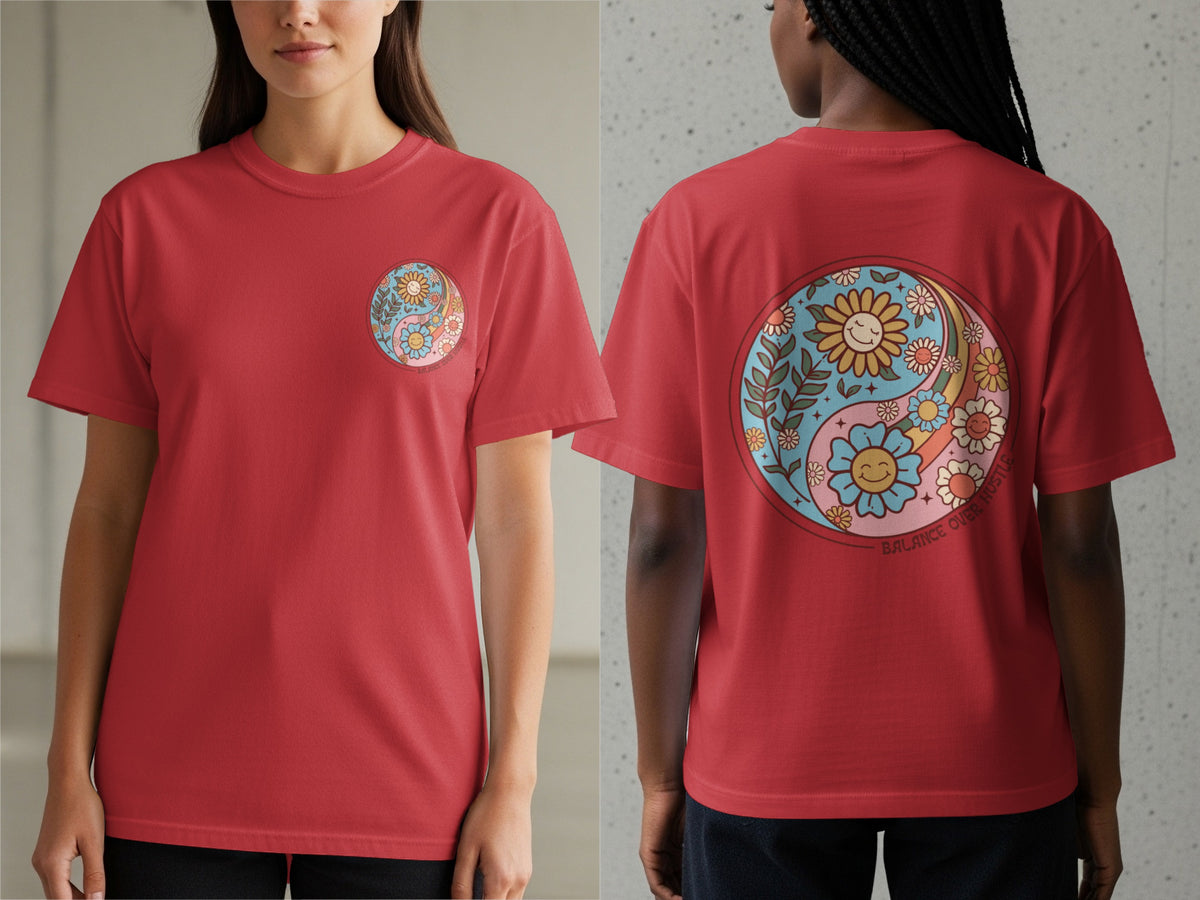 Red t-shirt with yin-yang design of smiling flowers and rainbows. Text reads "Balance Over Hustle".