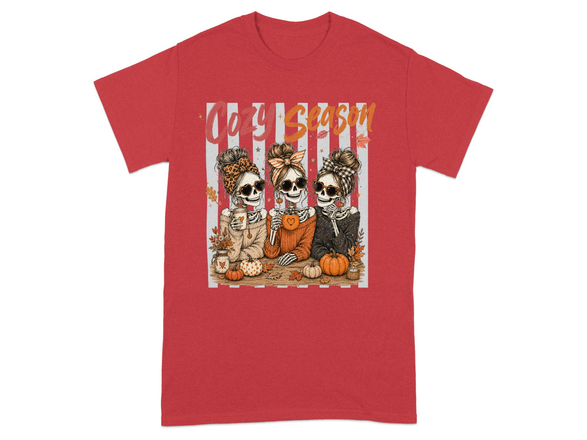 Three skeletons in cozy sweaters, sunglasses, and headbands enjoy fall drinks and pumpkins.