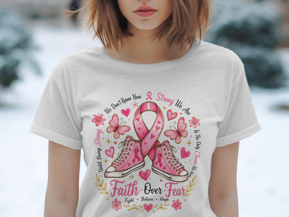 White t-shirt with pink ribbon, sneakers, butterflies, and text about strength and faith.