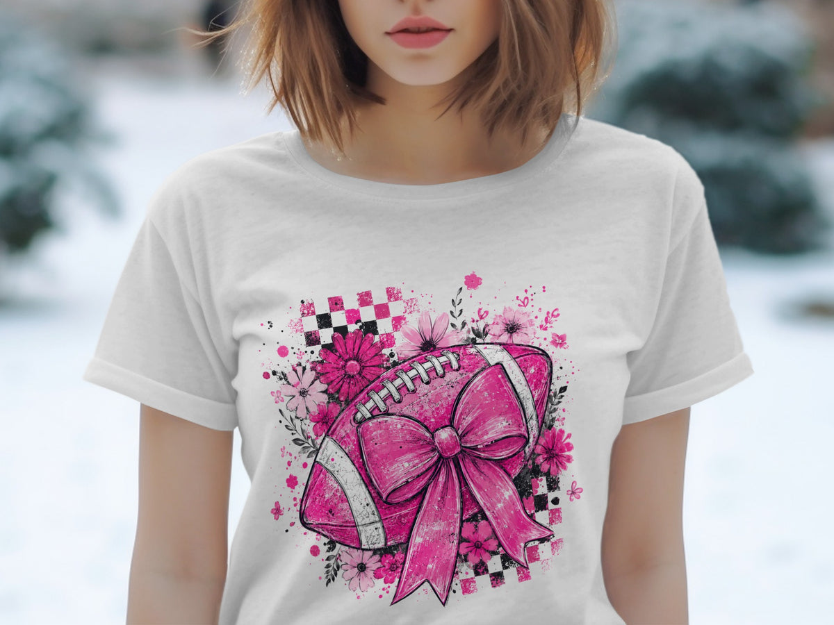 Pink football with bow, flowers, and checkered pattern on white t-shirt.