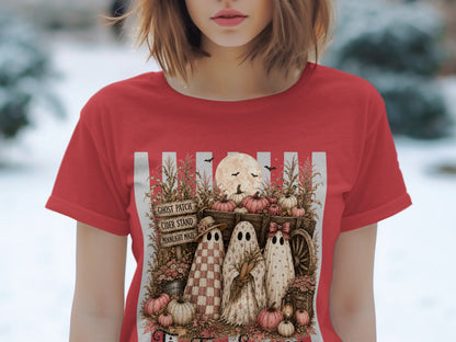 Three cartoon ghosts stand by a harvest cart with pumpkins, corn stalks, and a sign.