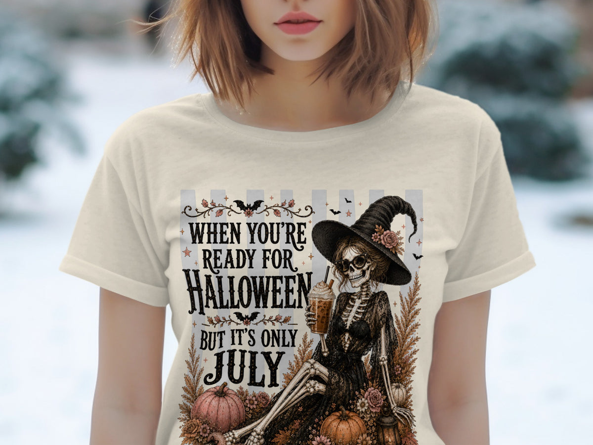 Skeleton witch with drink graphic on cream t-shirt, reads "When You're Ready For Halloween But It's Only July".