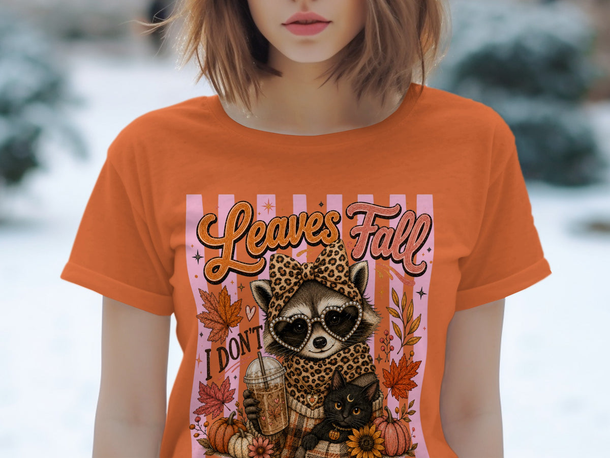 Orange t-shirt with raccoon, cat, pumpkin, and "Leaves Fall" text graphic.