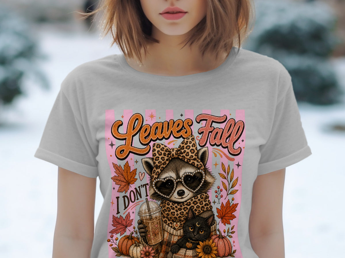 Raccoon in leopard print holding a coffee, with cat and pumpkins, says "Leaves Fall".