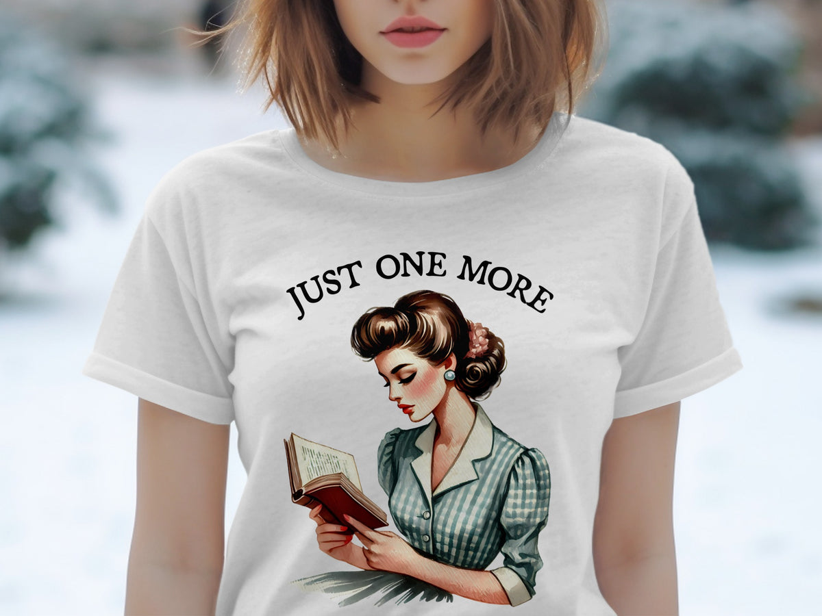 White t-shirt graphic of a woman reading a book with text "JUST ONE MORE".