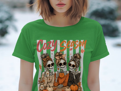 Three skeleton friends with buns and sunglasses enjoy "Cozy Season" with pumpkins and coffee.