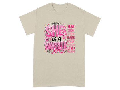 "SHE is a WARRIOR" with empowering words and a pink ribbon on a beige t-shirt.