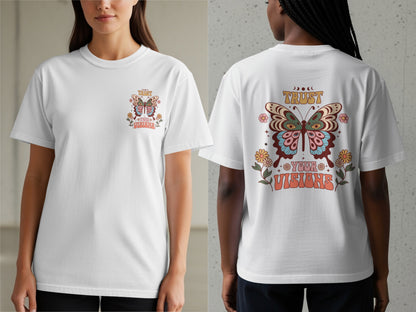 White t-shirt with a colorful butterfly graphic and text reading "TRUST YOUR VISIONS".