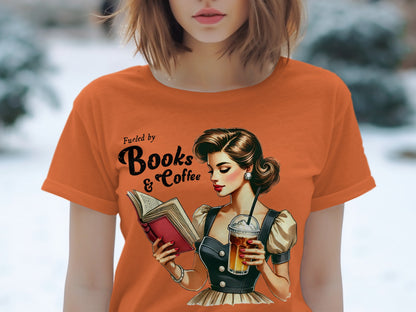 Orange t-shirt with "Fueled by Books & Coffee" and retro illustration of a woman reading.
