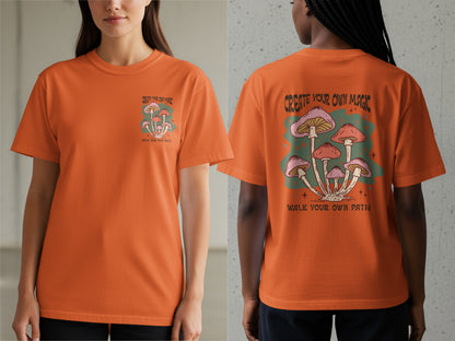 Orange t-shirt with mushroom graphic and text "CREATE YOUR OWN MAGIC WALK YOUR OWN PATH".