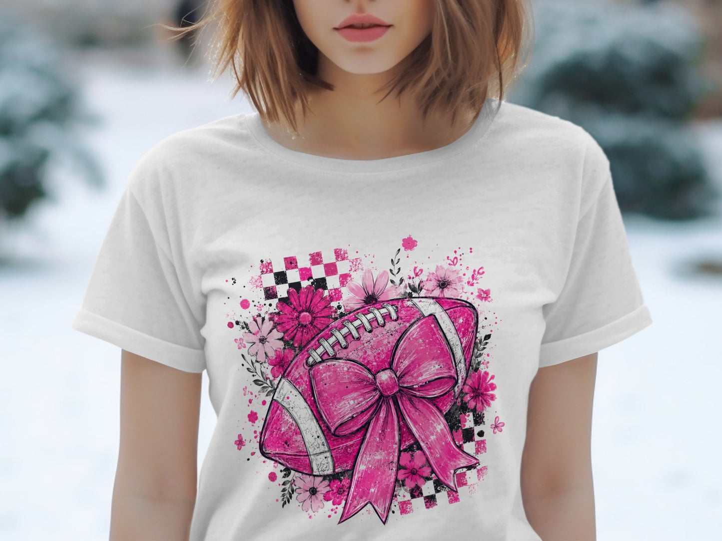 Pink football with bow, flowers, and checkered pattern on white t-shirt.