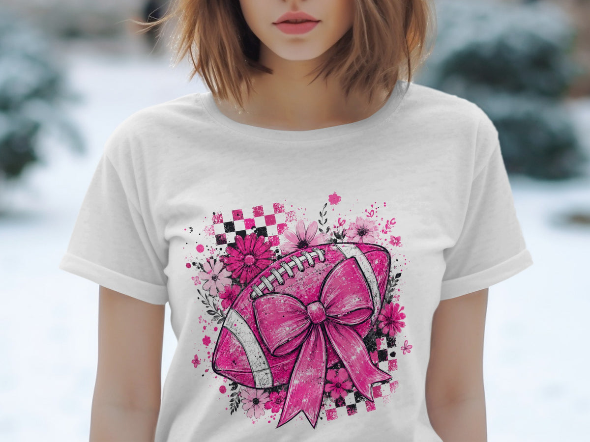 Pink football with bow, flowers, and checkered pattern on white t-shirt.