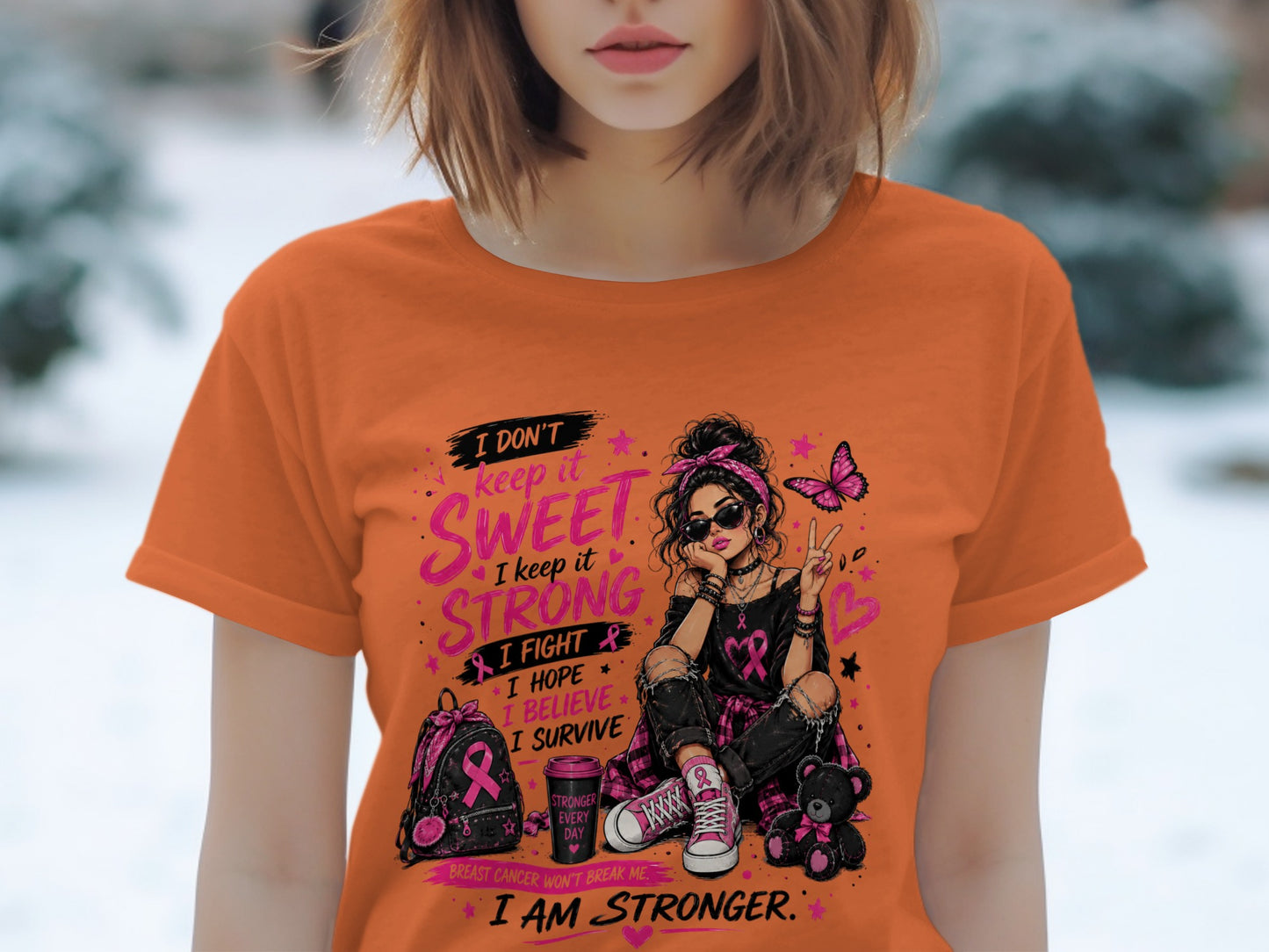 Orange t-shirt with graphic of a girl holding pink ribbons and inspirational text.