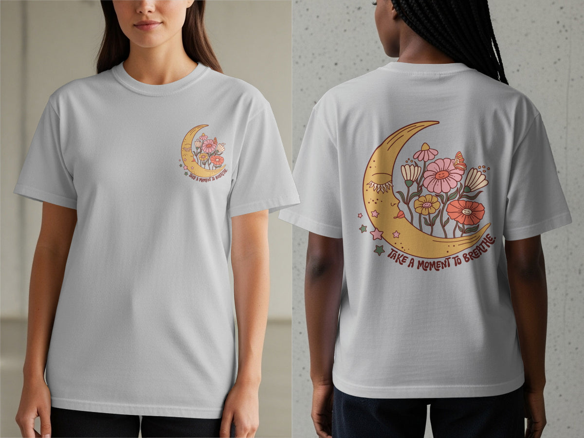 White t-shirt with a crescent moon, flowers, and stars graphic that says "TAKE A MOMENT TO BREATHE."