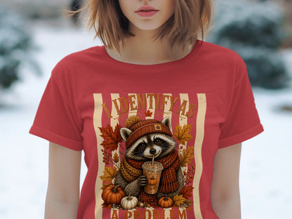 Raccoon wearing a scarf and hat drinks from a cup, surrounded by pumpkins and autumn leaves.