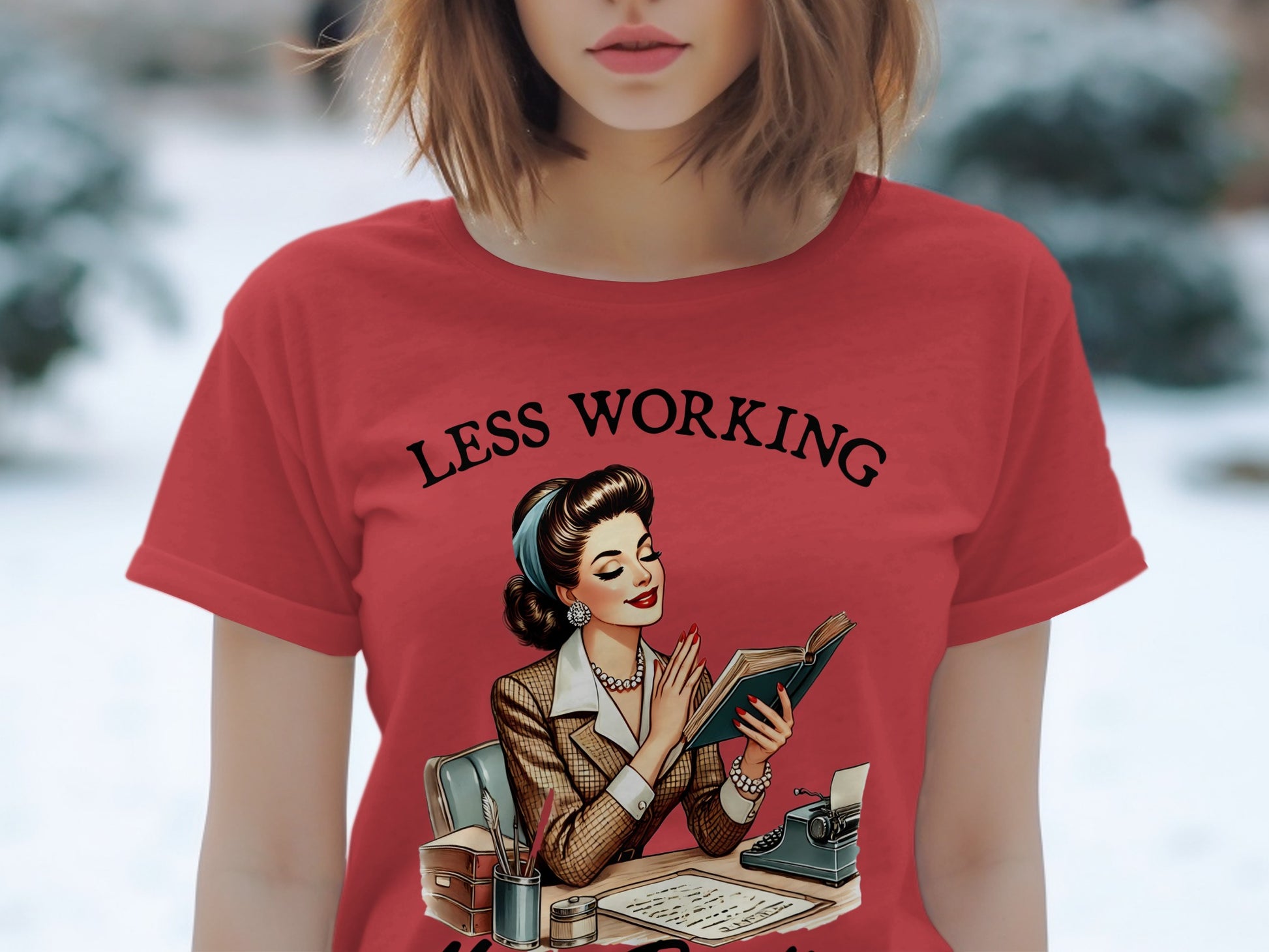 Red t-shirt with "Less Working" text and vintage woman reading at desk.