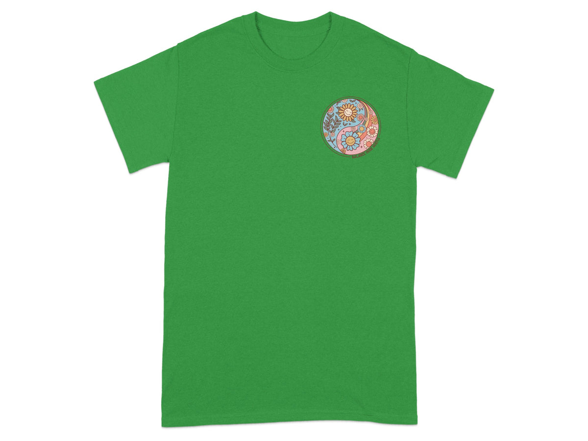 Green t-shirt with a circular yin-yang design of flowers, suns, and faces.