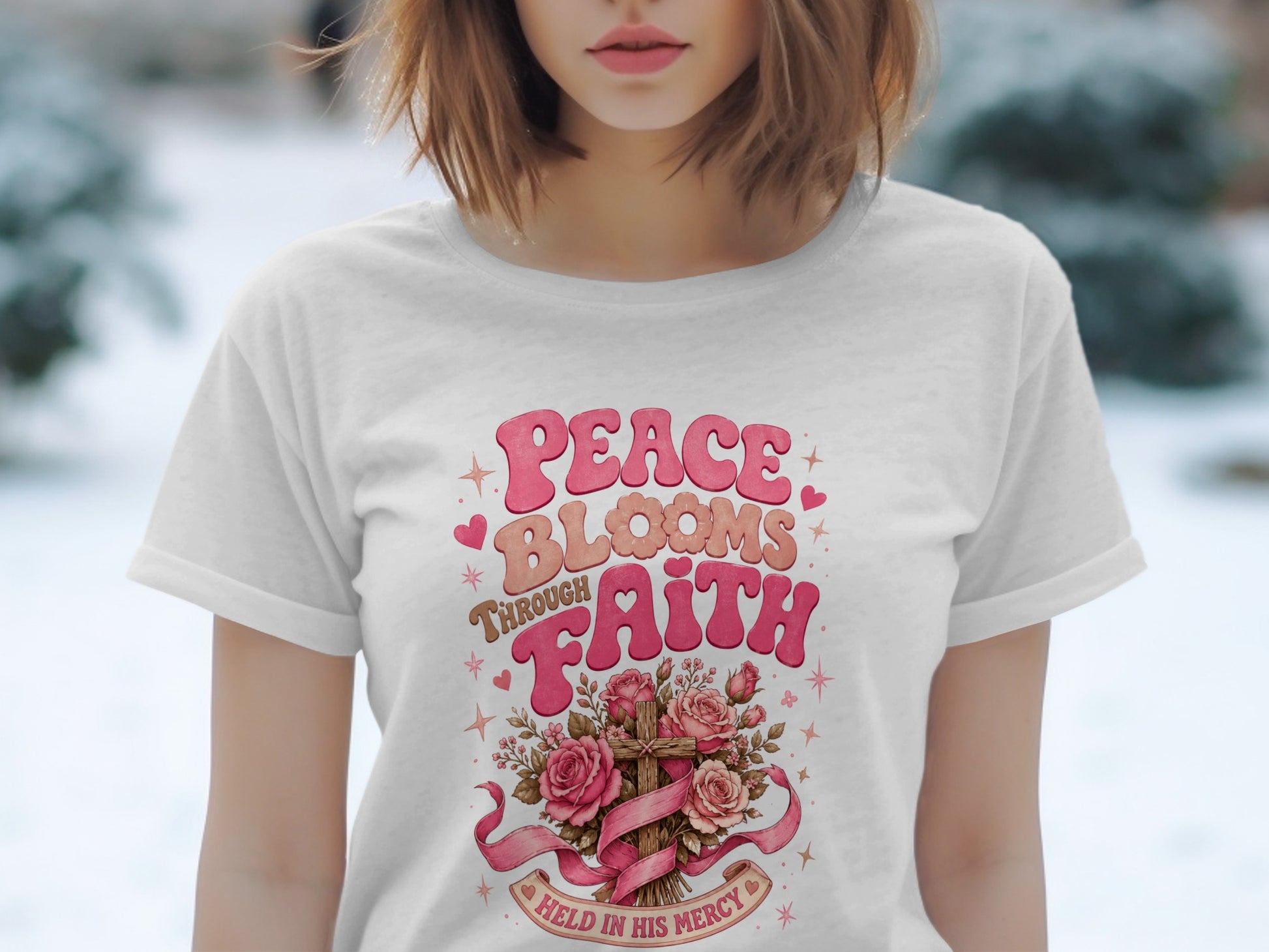 White t-shirt with "Peace Blooms Through Faith Held In His Mercy" text, cross, and roses.