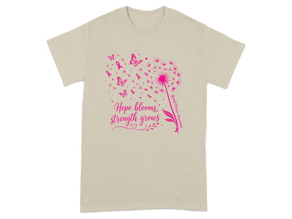 Tan t-shirt with pink dandelion, butterflies, ribbons, and text "Hope blooms, strength grows."