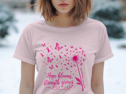 Pink t-shirt with a dandelion, butterflies, and pink ribbons, text says "Hope blooms, strength grows."